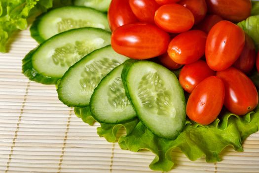 Ripe cherry tomatoes, cucumbers and lettuce closeup shot