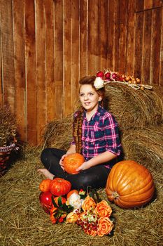Teen girl with a plait in a barn on the farm after harvest