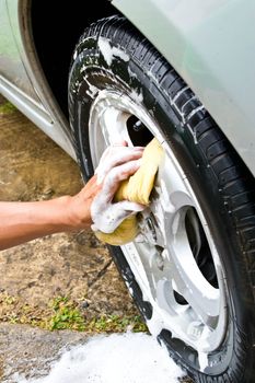 man washing car with a yellow sponge