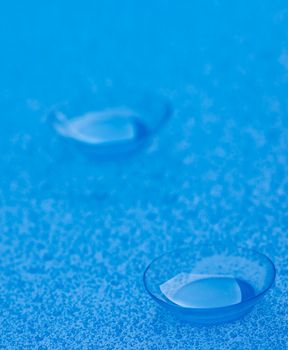 Pair of Contact Lenses with Water Droplets isolated on Blue background