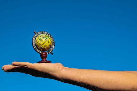 Vintage Old Globe Earth and Human Hand over a Blue Sky