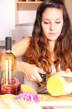 A young woman cutting vegetables ion the kitchen.