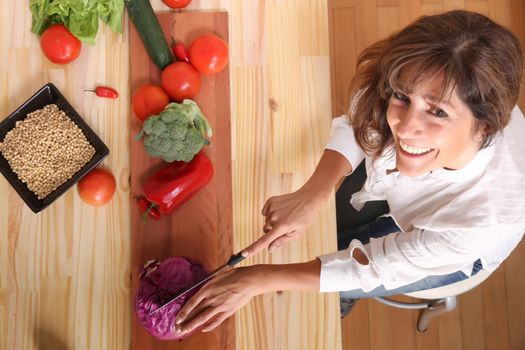 A beautiful mature woman cutting vegetables in the kitchen.