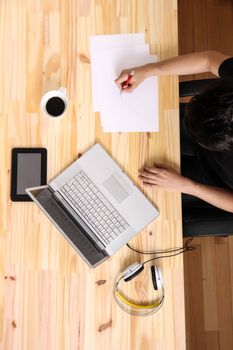 A young hispanic man working on a wooden desk with a laptop.