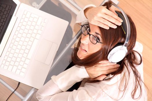 Business woman working on a Laptop while listening music with Headphones.