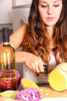 A young woman cutting vegetables ion the kitchen.