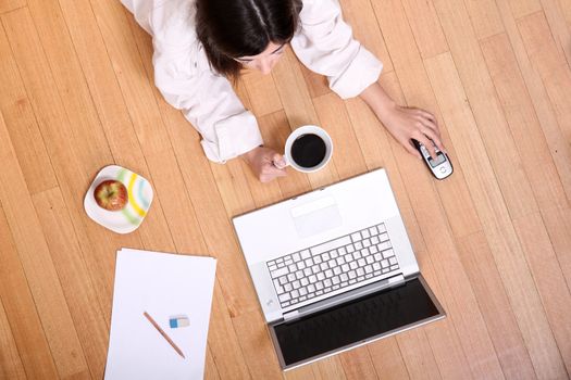 A young adult woman studying on the floor.