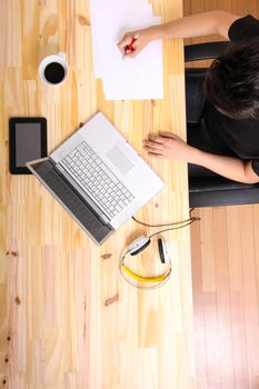 A young hispanic man working on a wooden desk with a laptop.