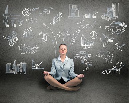 business woman meditating on floor, wall charts and diagrams are drawn