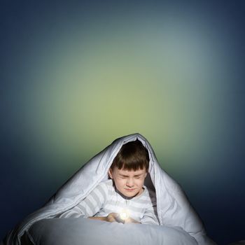 image of a frightened boy under the covers with a flashlight