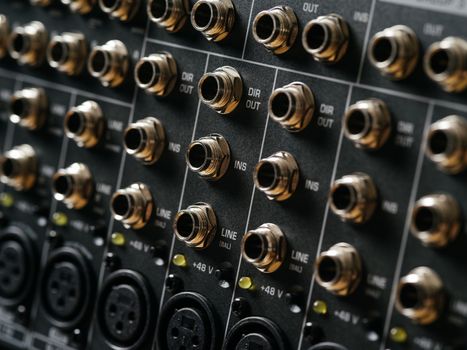 Macro photo of the rear panel of a recording studio mixer.
