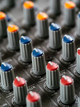 Macro photo of the knobs of a recording studio soundboard.
