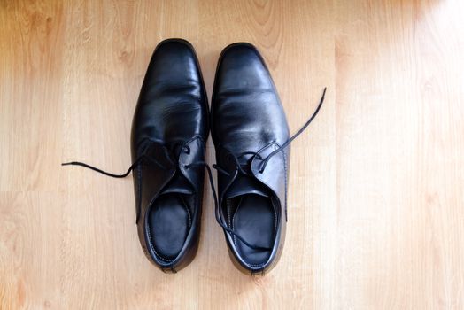 Shot from above, in wooden pattern background, a pair of men's black  elegant shoes for suit.