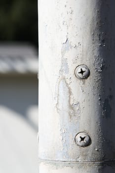 Rusty screw on a white pipe, close up