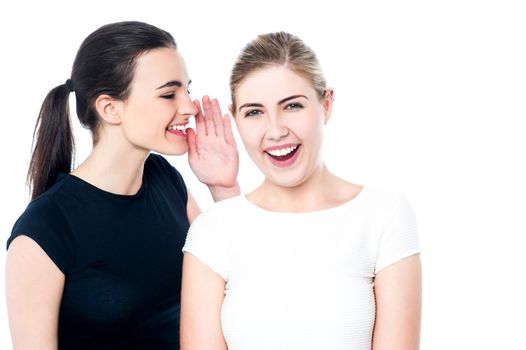 Two beautiful smiling girls sharing a secret