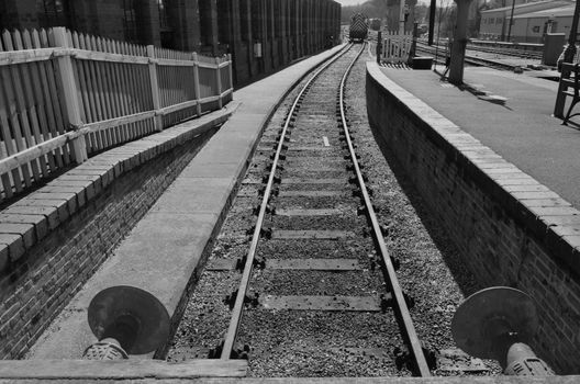 Black and white image of a uk railway siding showing buffers and platform.