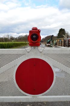 Old fashioned railway gate with red stop warning lamp on a rural English branch line.