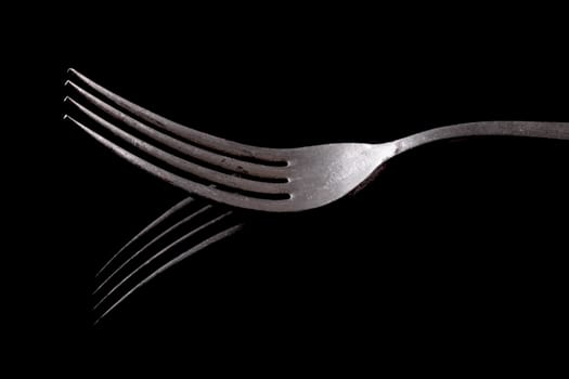old fork reflected on a black background
