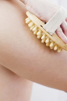 young woman making massage with wooden massager to prevent cellulite