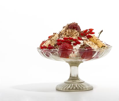 Ice cream dessert with fruit in a glass vase on a white background