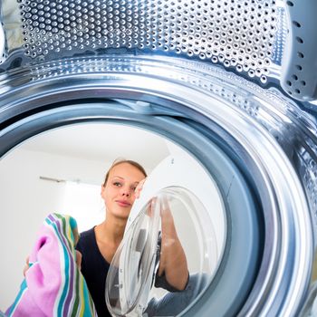 Housework: young woman doing laundry (shallow DOF; color toned image)