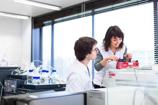 Two young researchers carrying out experiments in a lab (shallow DOF; color toned image)