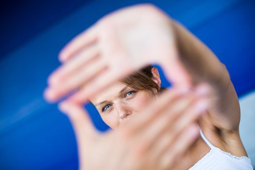 Pretty, young woman making a photo composing/shooting gesture with her hands