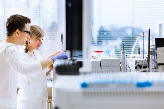 Two young researchers carrying out experiments in a lab (shallow DOF; color toned image)