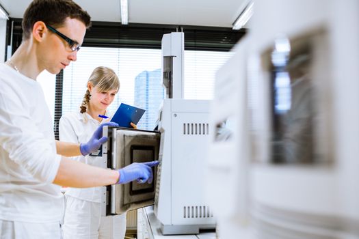 Two young researchers carrying out experiments in a lab (shallow DOF; color toned image)