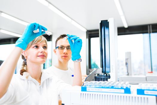 Two young researchers carrying out experiments in a lab (shallow DOF; color toned image)