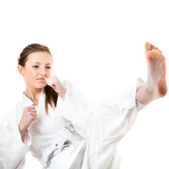 Beautiful caucasian, young, woman makes a kick in karate kimono on white background