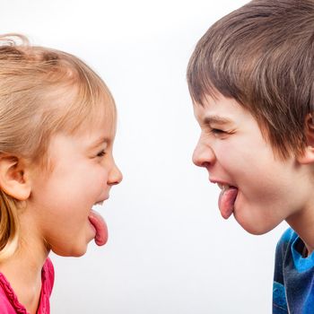 Sister and brother stick out tongues to each other