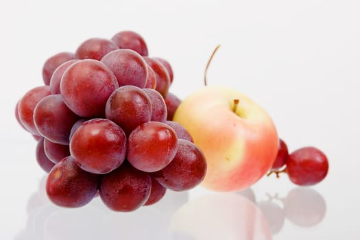 grapes and apple on a reflective surface