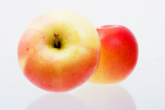 two ripe red apples on a reflective surface