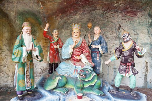 SINGAPORE - FEBRUARY 1, 2014: Di Zang Wang Ksitigarbha Buddha, in charge of the Tenth Court of Hell, with Attendants Statues Diorama at Haw Par Villa Theme Park. This theme park contains over 1,000 statues and 150 giant dioramas depicting scenes from Chinese mythology, folklore, legends, and history.
