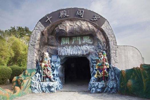 SINGAPORE - FEBRUARY 1, 2014: Entrance to the Ten Courts of Hell with Ox-Head and Horse-Face Guradians at Haw Par Villa Theme Park. This theme park contains over 1,000 statues and 150 giant dioramas depicting scenes from Chinese mythology, folklore, legends, and history.