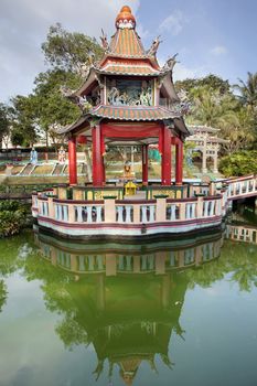 SINGAPORE - FEBRUARY 1, 2014: Buddha Statue Altar in Chinese Pavilion by the lake at Haw Par Villa Theme Park. This theme park contains over 1,000 statues and 150 giant dioramas depicting scenes from Chinese mythology, folklore, legends, and history.