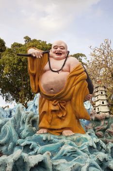 SINGAPORE - FEBRUARY 1, 2014: Ho Tai Laughing Buddha Statue at Haw Par Villa Theme Park. This theme park contains over 1,000 statues and 150 giant dioramas depicting scenes from Chinese mythology, folklore, legends, and history.