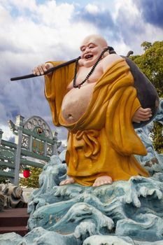 SINGAPORE - FEBRUARY 1, 2014: Ho Tai Laughing Buddha Statue by Gate at Haw Par Villa Theme Park. This theme park contains over 1,000 statues and 150 giant dioramas depicting scenes from Chinese mythology, folklore, legends, and history.