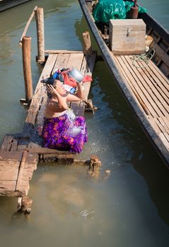 INLE LAKE, MYANMAR - 07 JAN 2014: Burmese local woman wash herself in Inle lake canal water. Traditionaly Burmese woman is washing in htamein (longyi) cloth.