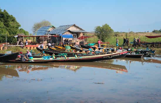 INLE LAKE, MYANMAR (Burma) - 07 JAN 2014: Many long wooden boats wait for passenger near traditional Burmese open market place.