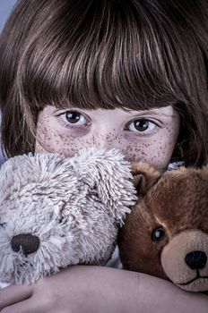 girl with freckles and two stuffed animals, teddy bears