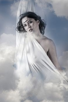 Fly, Beautiful woman in clouds, mithology concept. Brunette with long hair and white dress.