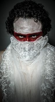 man covered with white lace veil, mask of red makeup