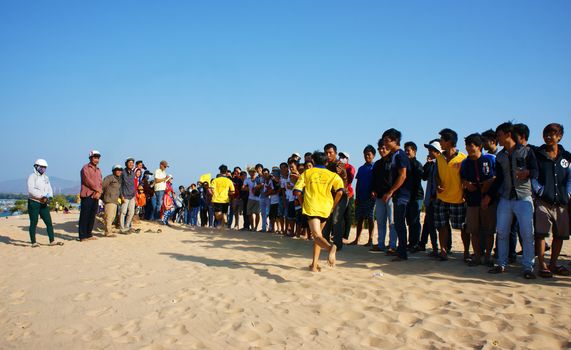 BINH THUAN, VIETNAM- FEB 14: Runner finish in marathon cross sand hill race, supporter standing in row to encourage, this's public sport activity to cheer healthy lifestyle, Viet Nam, Feb 14, 2014