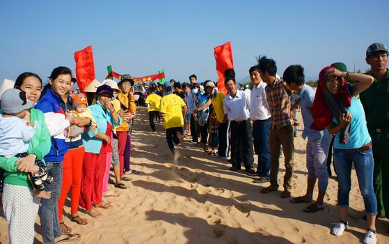 BINH THUAN, VIETNAM- FEB 14: Runner finish in marathon cross sand hill race, supporter standing in row to encourage, this's public sport activity to cheer healthy lifestyle, Viet Nam, Feb 14, 2014