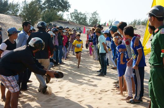 BINH THUAN, VIETNAM- FEB 14: Runner finish in marathon cross sand hill race, supporter standing in row to encourage, this's public sport activity to cheer healthy lifestyle, Viet Nam, Feb 14, 2014