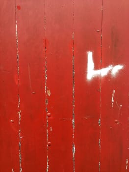 Closeup of red flaking paint on boards