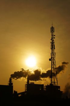 Black smoke from smoke stack of factory in industrial zone rose in to the air, it make polluted enviroment, the plant in silhouette at sunrise, atmosphere cover with waste exhaust