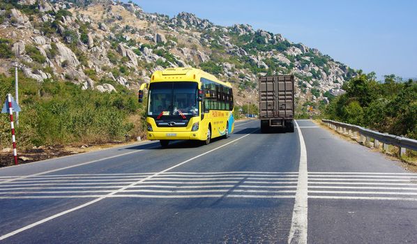 NINH THUAN, VIETNAM- JAN 22: Traffic of transport vehicle on highway 1A, the asphalt road beside impressive mountain under blue sky, passenger car and truck  moving on day, Viet Nam, Jan 22, 2014